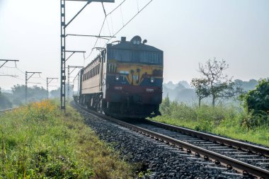 Pune, Hindistan - 08 Ekim 2023: Pune Hindistan yakınlarında bir WCAM3 elektrikli lokomotifi tarafından taşınan yolcu treni.