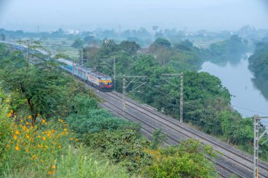 Pune, Hindistan - 15 Ekim 2023: Pune Hindistan yakınlarında bir WCAM3 elektrikli lokomotifi tarafından taşınan yolcu treni.