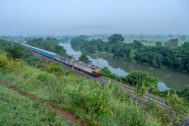 Pune, Hindistan - 15 Ekim 2023: Pune Hindistan yakınlarında bir WCAM3 elektrikli lokomotifi tarafından taşınan yolcu treni.