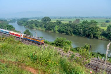 Pune, Hindistan - 15 Ekim 2023: Pune Hindistan yakınlarında bir WCAM3 elektrikli lokomotifi tarafından taşınan yolcu treni.