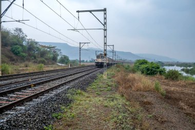 Pune, Hindistan - 07 Mayıs 2023: Pune Hindistan yakınlarında WAP7 elektrikli bir lokomotif tarafından taşınan yolcu treni.