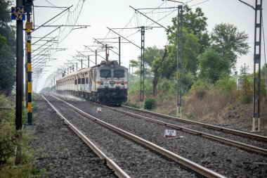 Pune, Hindistan - 18 Haziran 2023: Pune Hindistan yakınlarında WAP7 elektrikli bir lokomotif tarafından taşınan yolcu treni.