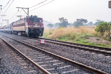 Pune, Hindistan - 05 Kasım 2023: Pune Hindistan yakınlarında WAP4 elektrikli bir lokomotif tarafından taşınan yolcu treni.
