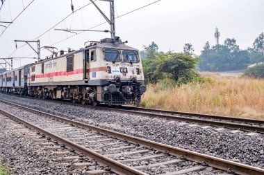 Pune, Hindistan - 05 Kasım 2023: Pune Hindistan yakınlarında WAP7 elektrikli bir lokomotif tarafından taşınan yolcu treni.