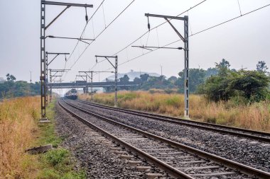 Pune, Hindistan - 05 Kasım 2023: Pune Hindistan yakınlarında WAP7 elektrikli bir lokomotif tarafından taşınan yolcu treni.