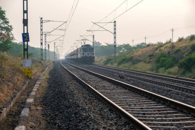 Pune, Hindistan - 13 Kasım 2023: Pune Hindistan yakınlarında WAP7 elektrikli bir lokomotif tarafından taşınan yolcu treni.