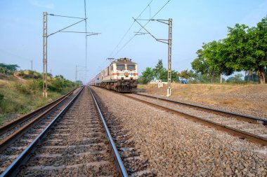 Pune, Hindistan - 13 Kasım 2023: Pune Hindistan yakınlarında WAP7 elektrikli bir lokomotif tarafından taşınan yolcu treni.