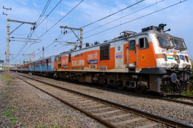 Pune, Hindistan - 26 Kasım 2023: Pune Hindistan yakınlarında WAP7 elektrikli bir lokomotif tarafından taşınan yolcu treni.