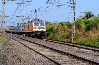 Pune, Hindistan - 26 Kasım 2023: Pune Hindistan yakınlarında WAP7 elektrikli bir lokomotif tarafından taşınan yolcu treni.