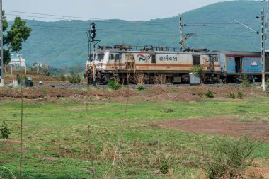Pune, Hindistan - 26 Mayıs 2024: Pune Hindistan yakınlarında WAP7 elektrikli bir lokomotif tarafından taşınan yolcu treni.