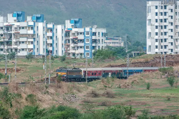 Pune, Hindistan - 26 Mayıs 2024: Pune Hindistan yakınlarında bir WCAM3 elektrikli lokomotifi tarafından taşınan yolcu treni.