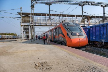 Satara, India - February 01 2025: Saffron coloured Vande Bharat Express at Satara India. This is a tri-weekly train between Pune and Kolhapur and also a tri-weekly train between Pune and Hubballi. clipart