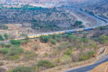 Pune, Hindistan - 01 Mart 2025: Pune Hindistan yakınlarında bir WCAM3 elektrikli lokomotifi tarafından taşınan yolcu treni.