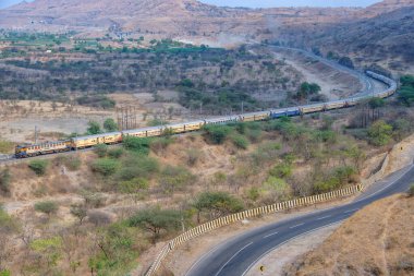 Pune, Hindistan - 01 Mart 2025: Pune Hindistan yakınlarında bir WCAM3 elektrikli lokomotifi tarafından taşınan yolcu treni.