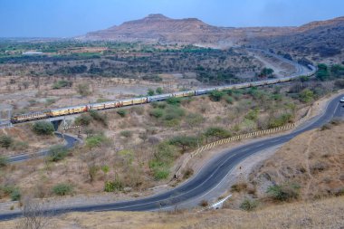 Pune, Hindistan - 01 Mart 2025: Pune Hindistan yakınlarında bir WCAM3 elektrikli lokomotifi tarafından taşınan yolcu treni.