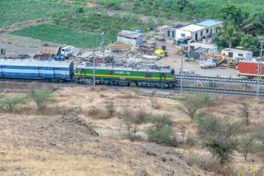 Pune, Hindistan - 01 Mart 2025: Pune Hindistan yakınlarında bir WAG9 elektrikli lokomotifi tarafından taşınan bir araba nakliye treni.