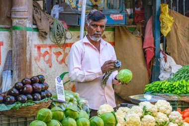 Pune, Hindistan - 09 Mart 2025: Pune India 'daki Mandai pazarında erkek satıcı ve QR kodlu bir sebze tezgahında sahne.
