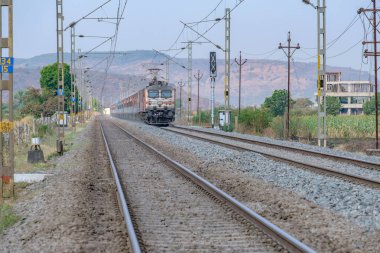 Pune, Hindistan - 15 Mart 2025: Pune Hindistan yakınlarında WAP7 elektrikli bir lokomotif tarafından taşınan yolcu treni.