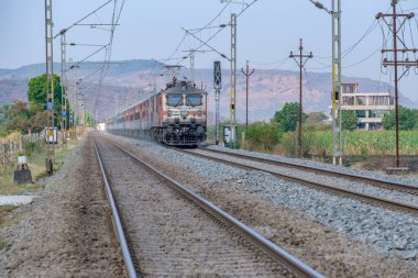 Pune, Hindistan - 15 Mart 2025: Pune Hindistan yakınlarında WAP7 elektrikli bir lokomotif tarafından taşınan yolcu treni.