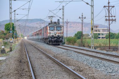 Pune, Hindistan - 15 Mart 2025: Pune Hindistan yakınlarında WAP7 elektrikli bir lokomotif tarafından taşınan yolcu treni.