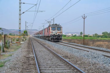 Pune, Hindistan - 15 Mart 2025: Pune Hindistan yakınlarında WAP7 elektrikli bir lokomotif tarafından taşınan yolcu treni.