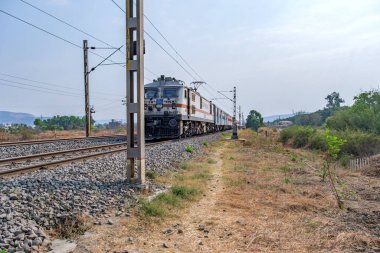 Pune, Hindistan - 15 Mart 2025: Pune Hindistan yakınlarında WAP7 elektrikli bir lokomotif tarafından taşınan yolcu treni.