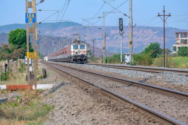 Pune, Hindistan - 15 Mart 2025: Pune Hindistan yakınlarında WAP7 elektrikli bir lokomotif tarafından taşınan yolcu treni.
