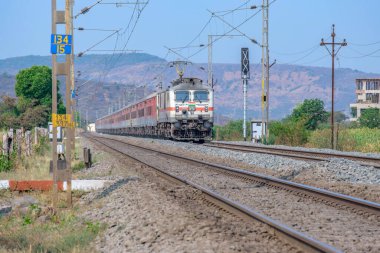 Pune, Hindistan - 15 Mart 2025: Pune Hindistan yakınlarında WAP7 elektrikli bir lokomotif tarafından taşınan yolcu treni.