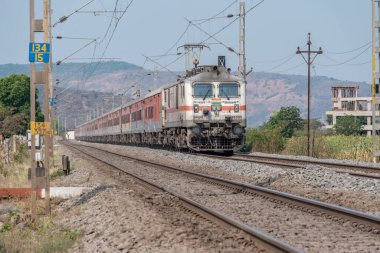Pune, Hindistan - 15 Mart 2025: Pune Hindistan yakınlarında WAP7 elektrikli bir lokomotif tarafından taşınan yolcu treni.