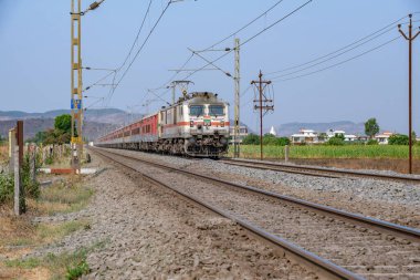 Pune, Hindistan - 15 Mart 2025: Pune Hindistan yakınlarında WAP7 elektrikli bir lokomotif tarafından taşınan yolcu treni.