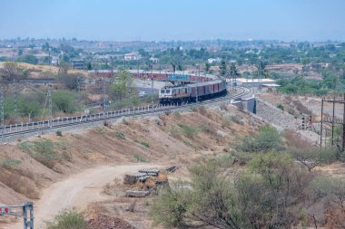 Pune, Hindistan - 22 Mart 2025: Pune Hindistan yakınlarında WAP7 elektrikli bir lokomotif tarafından taşınan yolcu treni.