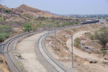 Pune, Hindistan - 22 Mart 2025: Pune Hindistan yakınlarında WAP7 elektrikli bir lokomotif tarafından taşınan yolcu treni.
