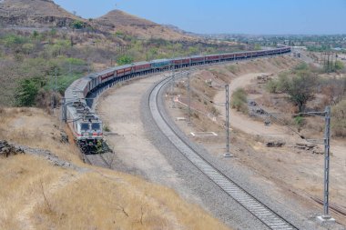Pune, Hindistan - 22 Mart 2025: Pune Hindistan yakınlarında WAP7 elektrikli bir lokomotif tarafından taşınan yolcu treni.