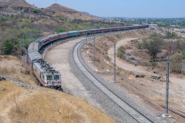 Pune, Hindistan - 22 Mart 2025: Pune Hindistan yakınlarında WAP7 elektrikli bir lokomotif tarafından taşınan yolcu treni.