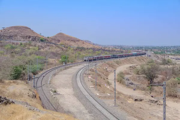 Pune, Hindistan - 22 Mart 2025: Pune Hindistan yakınlarında WAP7 elektrikli bir lokomotif tarafından taşınan yolcu treni.