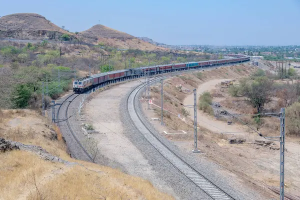 Pune, Hindistan - 22 Mart 2025: Pune Hindistan yakınlarında WAP7 elektrikli bir lokomotif tarafından taşınan yolcu treni.