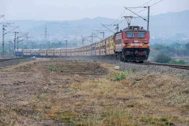 Pune, Hindistan - 31 Mart 2025: Pune Hindistan yakınlarında WAP4 elektrikli bir lokomotif tarafından taşınan yolcu treni.