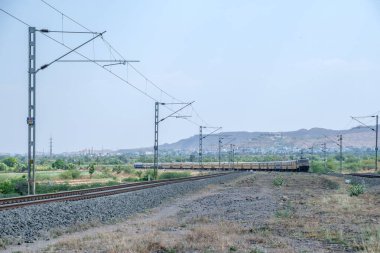 Pune, Hindistan - 12 Nisan 2025: Pune Hindistan yakınlarında WAP4 elektrikli bir lokomotif tarafından taşınan yolcu treni.