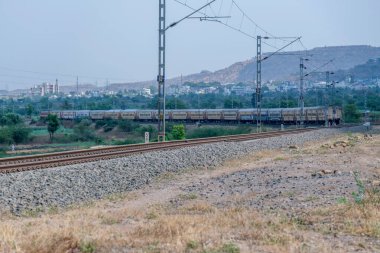 Pune, Hindistan - 12 Nisan 2025: Pune Hindistan yakınlarında WAP4 elektrikli bir lokomotif tarafından taşınan yolcu treni.