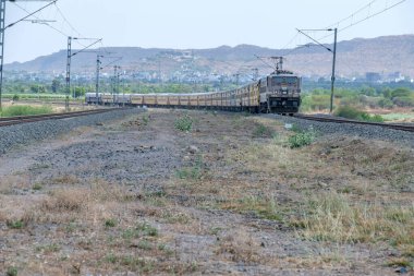 Pune, Hindistan - 12 Nisan 2025: Pune Hindistan yakınlarında WAP4 elektrikli bir lokomotif tarafından taşınan yolcu treni.