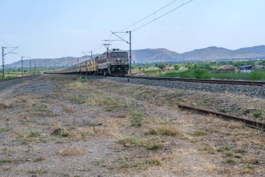 Pune, Hindistan - 12 Nisan 2025: Pune Hindistan yakınlarında WAP4 elektrikli bir lokomotif tarafından taşınan yolcu treni.