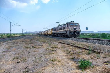 Pune, Hindistan - 12 Nisan 2025: Pune Hindistan yakınlarında WAP4 elektrikli bir lokomotif tarafından taşınan yolcu treni.