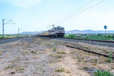 Pune, Hindistan - 12 Nisan 2025: Pune Hindistan yakınlarında WAP4 elektrikli bir lokomotif tarafından taşınan yolcu treni.