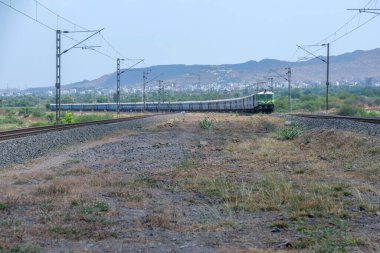 Pune, Hindistan - 12 Nisan 2025: Pune Hindistan yakınlarında bir WAG9 elektrikli lokomotifi tarafından taşınan bir araba nakliye treni.
