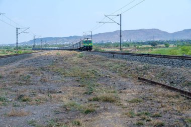 Pune, Hindistan - 12 Nisan 2025: Pune Hindistan yakınlarında bir WAG9 elektrikli lokomotifi tarafından taşınan bir araba nakliye treni.