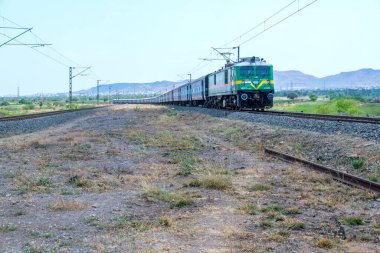 Pune, Hindistan - 12 Nisan 2025: Pune Hindistan yakınlarında bir WAG9 elektrikli lokomotifi tarafından taşınan bir araba nakliye treni.