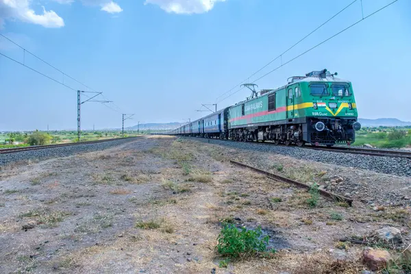 Pune, Hindistan - 12 Nisan 2025: Pune Hindistan yakınlarında bir WAG9 elektrikli lokomotifi tarafından taşınan bir araba nakliye treni.