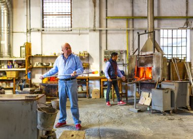 MURANO, İtalya, 20 Şubat 2023: Murano cam fabrikasının içinde, usta bir cam ustası, İtalya 'daki cam üretim sürecini gösteriyor.