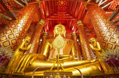 Ayutthaya, Tayland 'daki Phanan Choeng tapınağının içinde kırmızı ve altın süslerle süslenmiş büyük altın bir Buda heykeli.