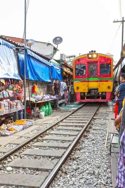 BANGKOK, THAILAND, 25 Ağustos 2024: Tayland 'daki hareketli Maeklong Demiryolu Pazarı' na renkli bir tren yaklaşıyor.